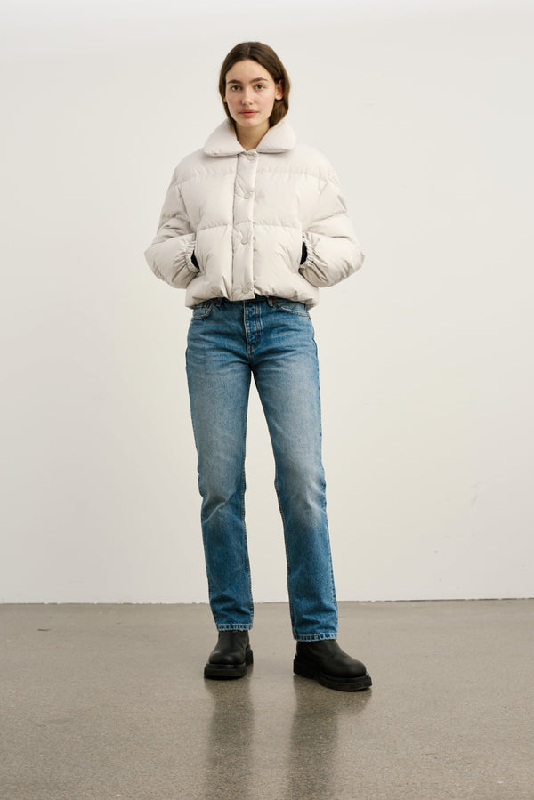 A model wears a light beige puffer jacket with a collar, paired with blue jeans and black boots, showcasing MEOTINE's stylish outerwear.