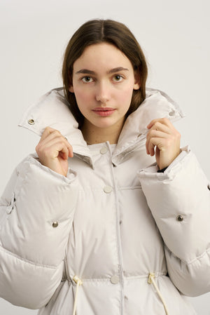 A model wearing a light-colored puffer jacket with a high collar, showcasing the stylish design of MEOTINE outerwear.