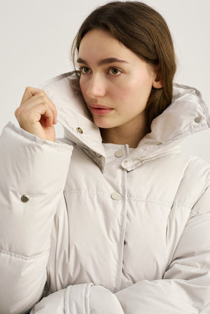 A model showcases a stylish, oversized white puffer jacket with a high collar, perfect for winter, by MEOTINE.