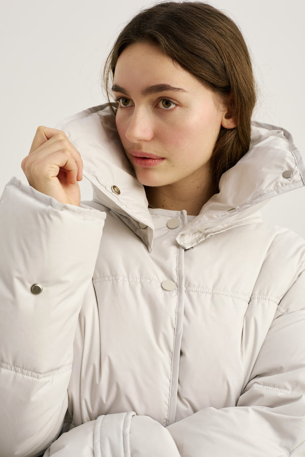 A model showcases a stylish, oversized white puffer jacket with a high collar, perfect for winter, by MEOTINE.