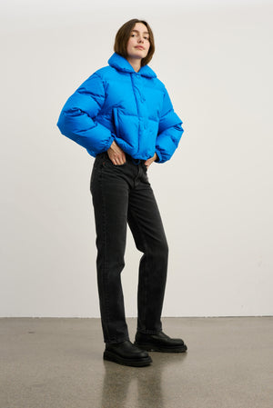 A model showcases a vibrant blue puffer jacket paired with black jeans and chunky boots, embodying MEOTINE's stylish winter look.