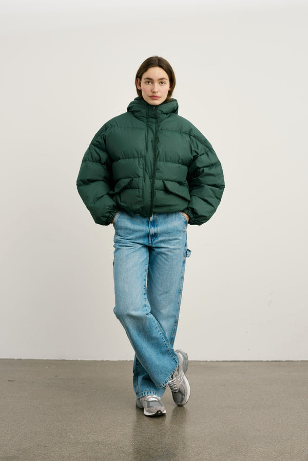 A model wears a stylish green puffer jacket paired with relaxed-fit jeans, showcasing MEOTINE's trendy winter fashion.