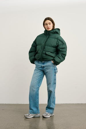 A model wears a green puffer jacket paired with light blue wide-leg jeans and sneakers, showcasing MEOTINE's stylish winter look.