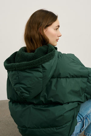 A model showcases a cozy green puffer jacket with a plush hood, perfect for chilly days, by MEOTINE.