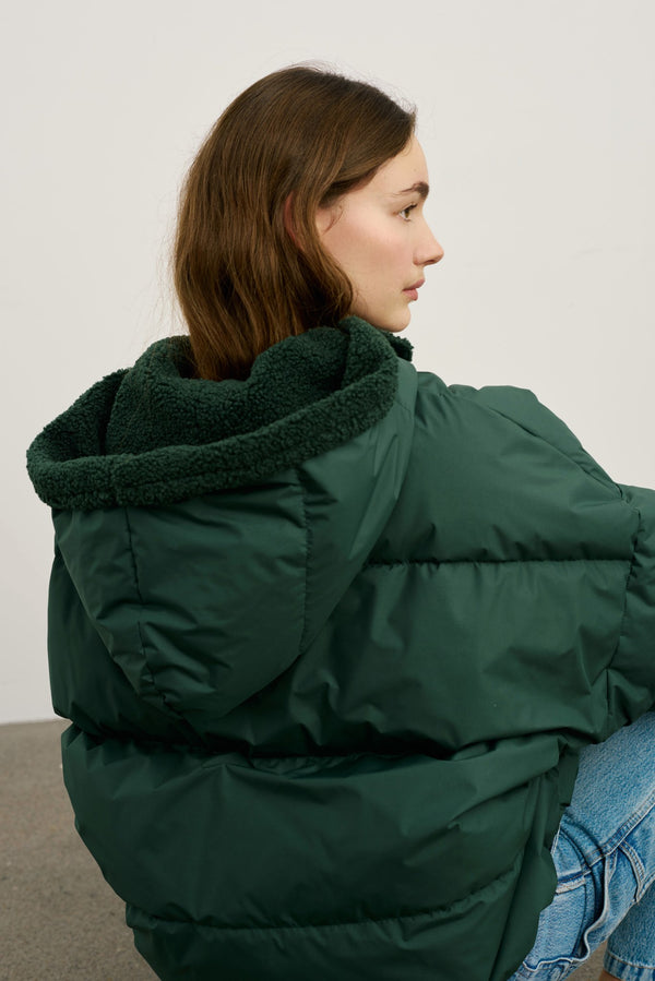 A model showcases a cozy green puffer jacket with a plush hood, perfect for chilly days, by MEOTINE.