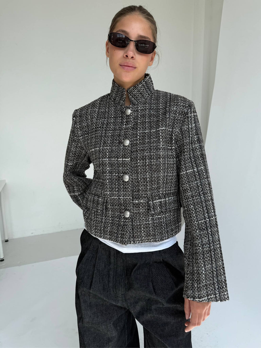 Chic cropped jacket in black and white tweed with large buttons, paired with relaxed dark trousers and stylish sunglasses. MEOTINE.