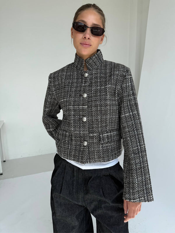 Chic cropped jacket in black and white tweed with large buttons, paired with relaxed dark trousers and stylish sunglasses. MEOTINE.