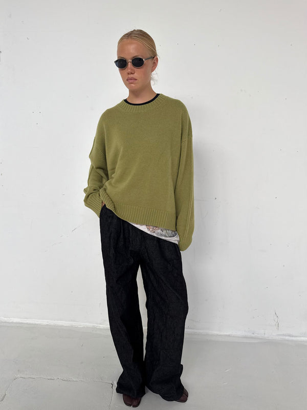 A model wears a relaxed olive green sweater and black wide-leg pants, showcasing a casual yet stylish look by MEOTINE.