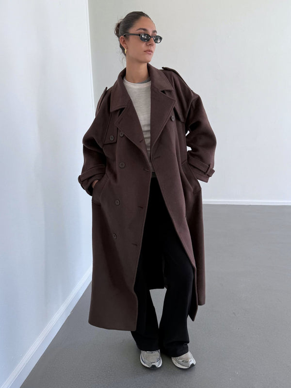 A model showcases a stylish brown oversized coat paired with a light top and black pants, exuding a chic vibe for MEOTINE.