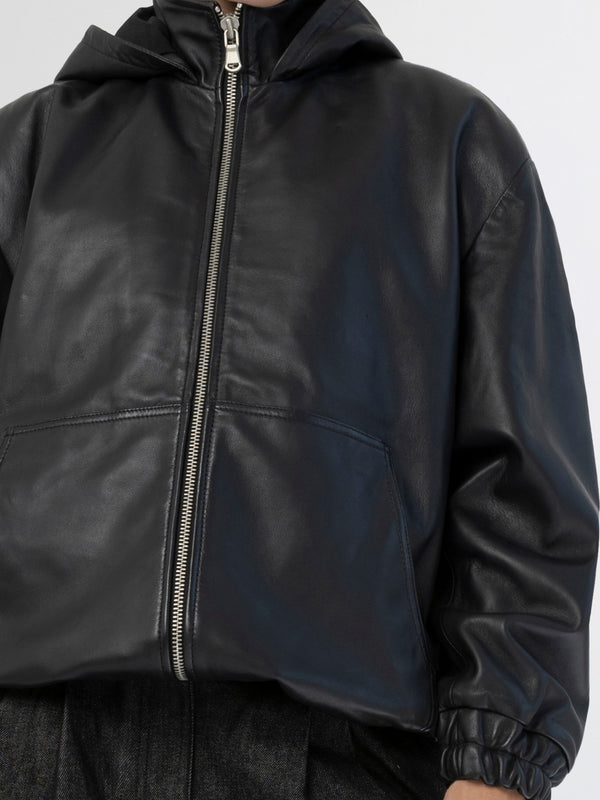 A model wears a stylish black leather jacket with a hood and zip closure, showcasing MEOTINE's modern design.