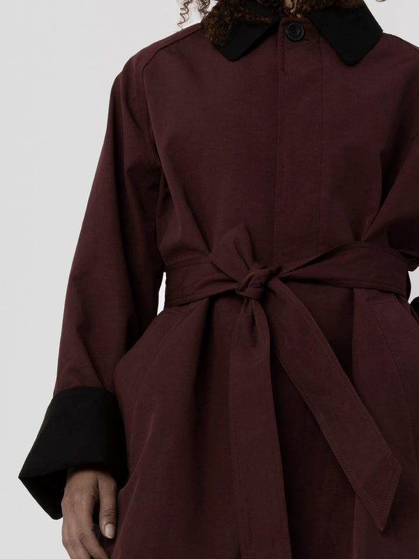 A stylish maroon coat with a black collar and sleeves, featuring a tied waist for a flattering fit. By MEOTINE.