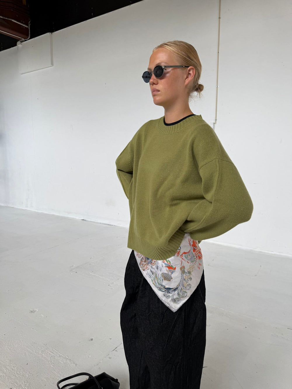A model wears a relaxed olive green sweater and black wide-leg pants, showcasing a casual yet stylish look by MEOTINE.