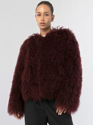 A model showcases a plush, burgundy MEOTINE faux fur jacket with a relaxed fit and long sleeves, perfect for cozy styling.