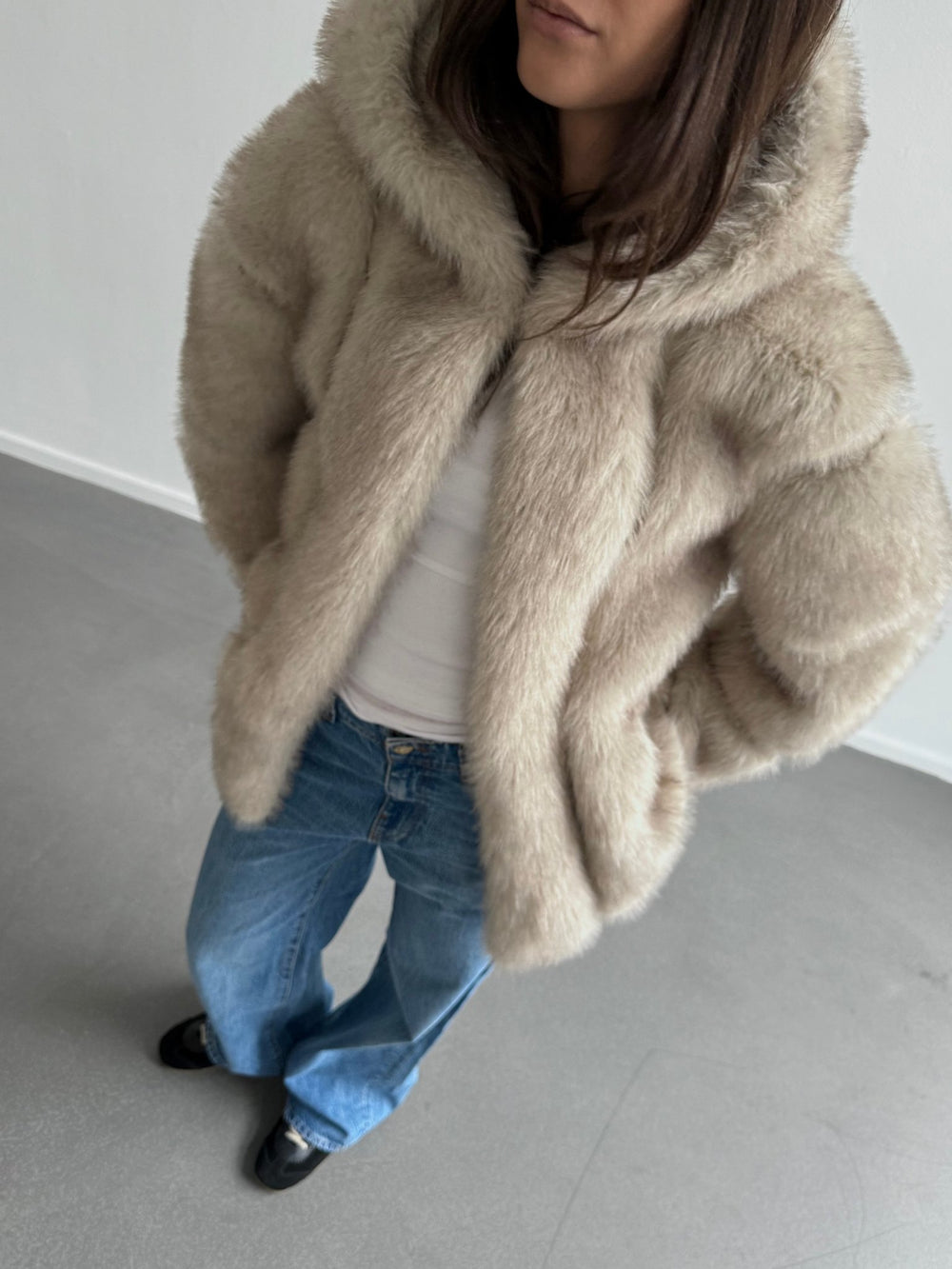 A model wearing a cozy beige faux fur jacket with a hood, paired with light blue jeans, showcasing MEOTINE's stylish design.
