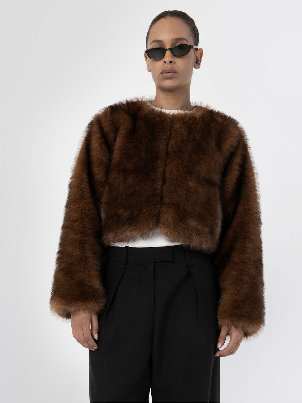 A model showcases a stylish brown fur jacket by MEOTINE, paired with a casual top and sleek pants, exuding elegance and warmth.