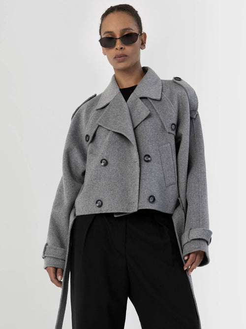 Stylish gray cropped trench coat with double-breasted buttons, paired with sleek black pants and sunglasses, by MEOTINE.
