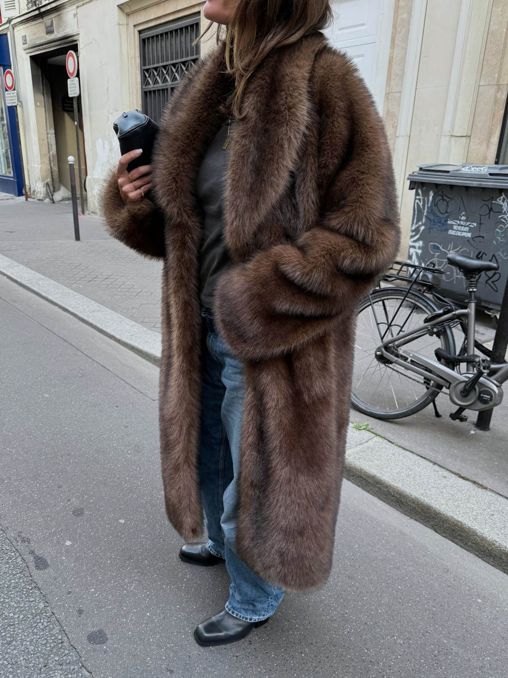 A woman walks down the street in a luxurious brown fur coat, paired with jeans and black boots, showcasing MEOTINE's elegant style.