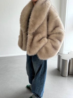 A model wears a luxurious beige faux fur coat by MEOTINE, paired with relaxed denim jeans, showcasing a chic, cozy look.