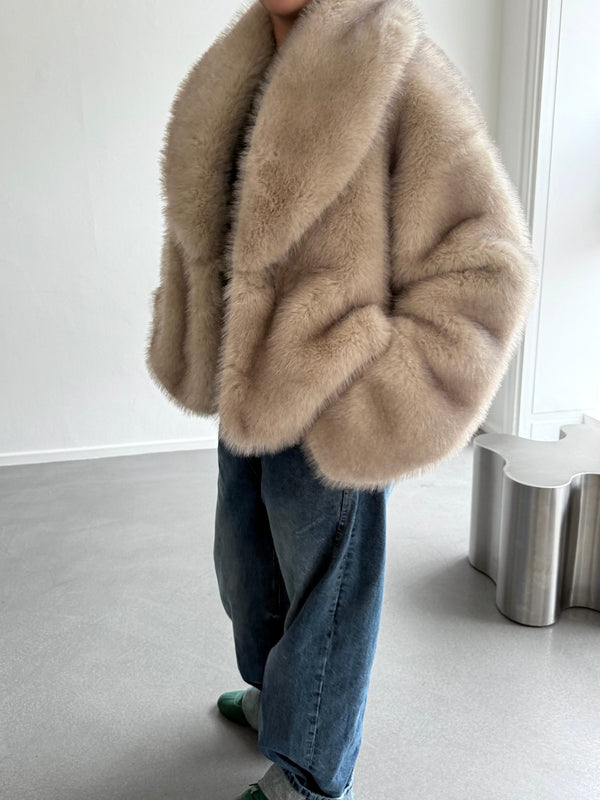 A model wears a luxurious beige faux fur coat by MEOTINE, paired with relaxed denim jeans, showcasing a chic, cozy look.