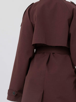 Stylish brown trench coat with a cropped back design, featuring a belted waist and buttoned cuffs, by MEOTINE.