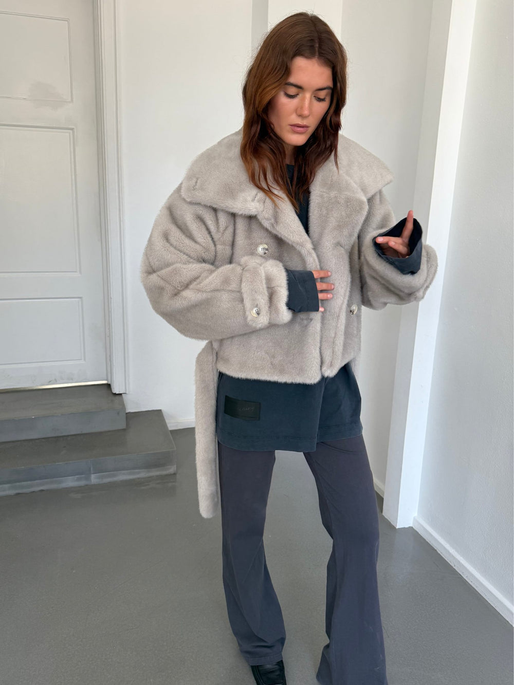 Cozy beige faux fur jacket with a double-breasted design and tie waist, styled with sleek sunglasses. MEOTINE brand.