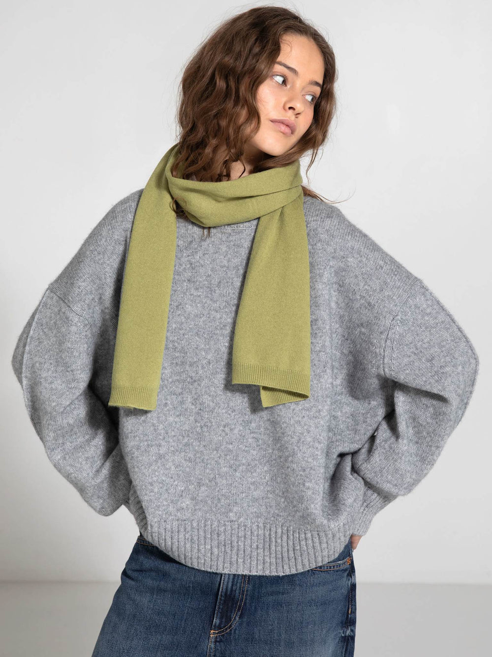 A model wearing a cozy gray oversized sweater with a soft green scarf, showcasing MEOTINE's stylish winter collection.