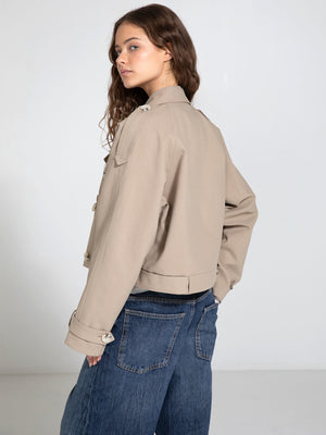 A model showcases a stylish beige cropped jacket with button details, paired with wide-leg denim jeans, embodying MEOTINE's chic aesthetic.