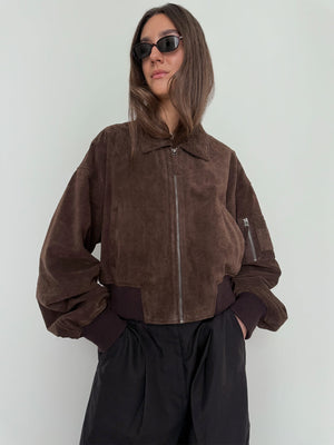 Brown suede bomber jacket with a zip front and ribbed cuffs, styled with black pants and sunglasses, by MEOTINE.