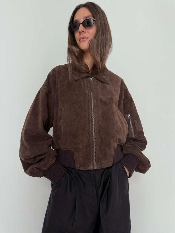 Brown suede bomber jacket with a zip front and ribbed cuffs, styled with black pants and sunglasses, by MEOTINE.