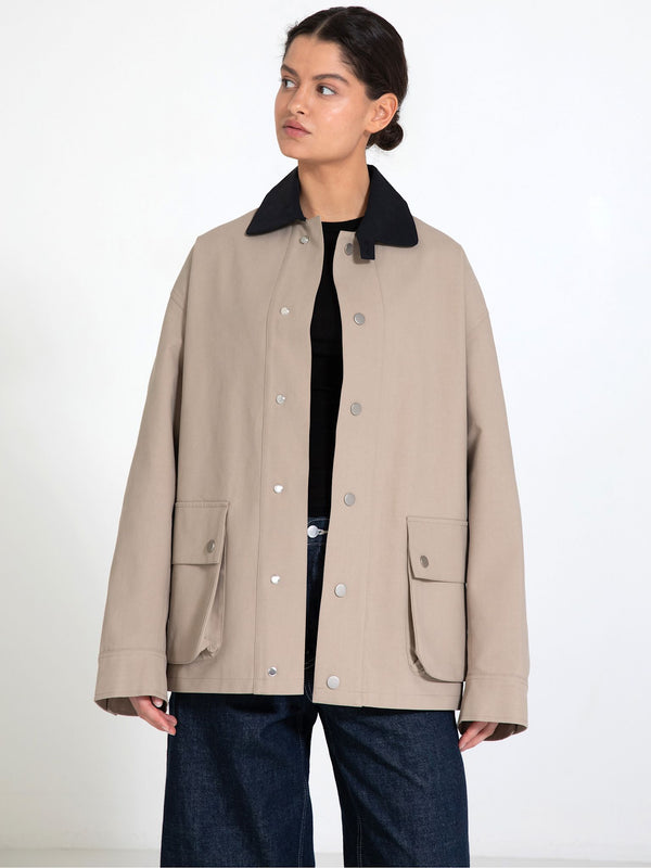 A model showcases a beige MEOTINE jacket with a black collar, featuring large front pockets and a relaxed fit.