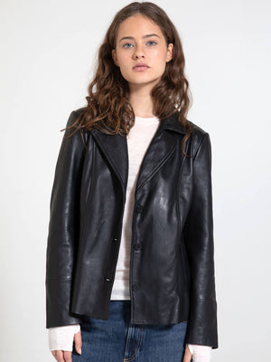 A stylish black leather jacket from MEOTINE, featuring a tailored fit and button closure, worn by a model with wavy hair.