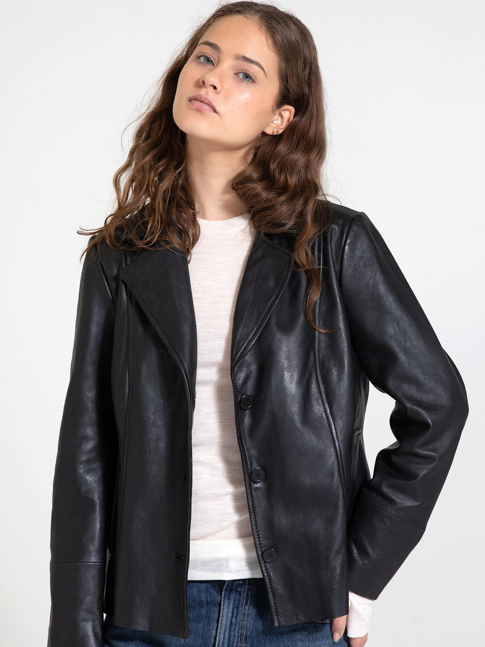 A stylish black leather jacket from MEOTINE, featuring a tailored fit and button closure, worn by a model with wavy hair.