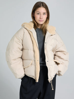 A model wears a cozy beige MEOTINE puffer jacket with a soft fur collar, paired with a gray top and black pants.