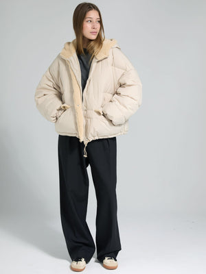A model wears a cozy beige puffer jacket with a soft collar, paired with black wide-leg pants, showcasing MEOTINE's stylish outerwear.