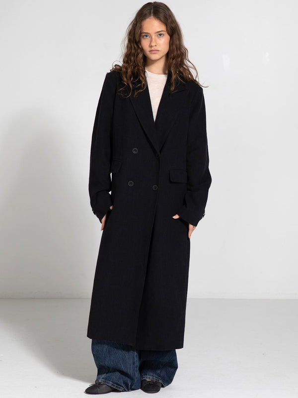 A model wearing a long black double-breasted coat paired with wide-leg jeans, showcasing MEOTINE's stylish outerwear.