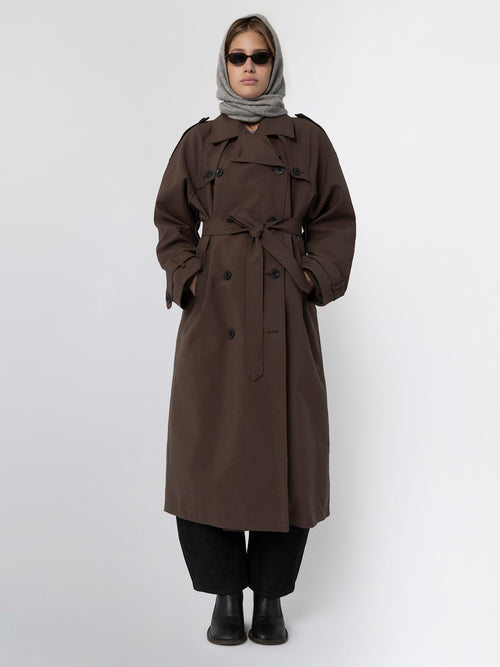 A model wearing a brown trench coat with a belt, paired with a gray scarf and sunglasses, showcasing MEOTINE's stylish outerwear.