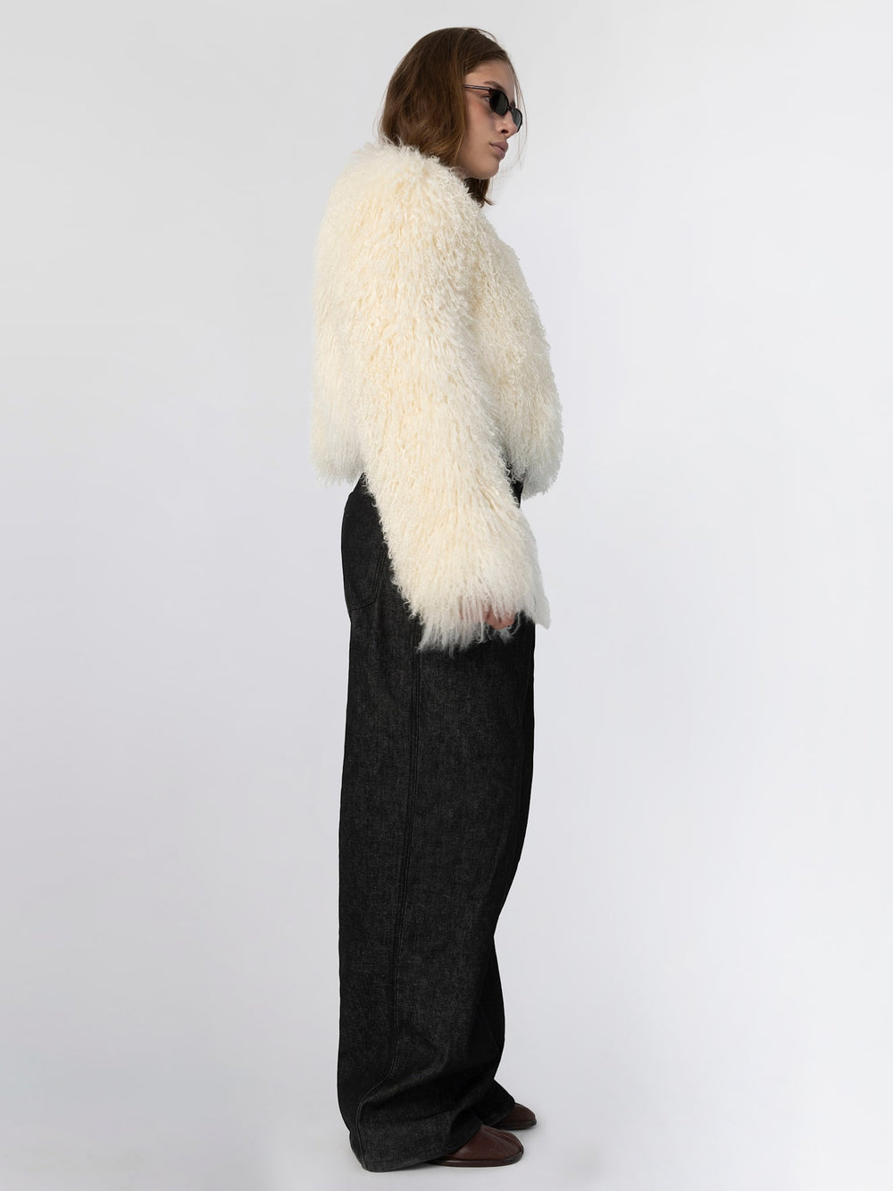 Cozy cream-colored fluffy sweater with oversized sleeves, styled with dark high-waisted pants and sunglasses, by MEOTINE.