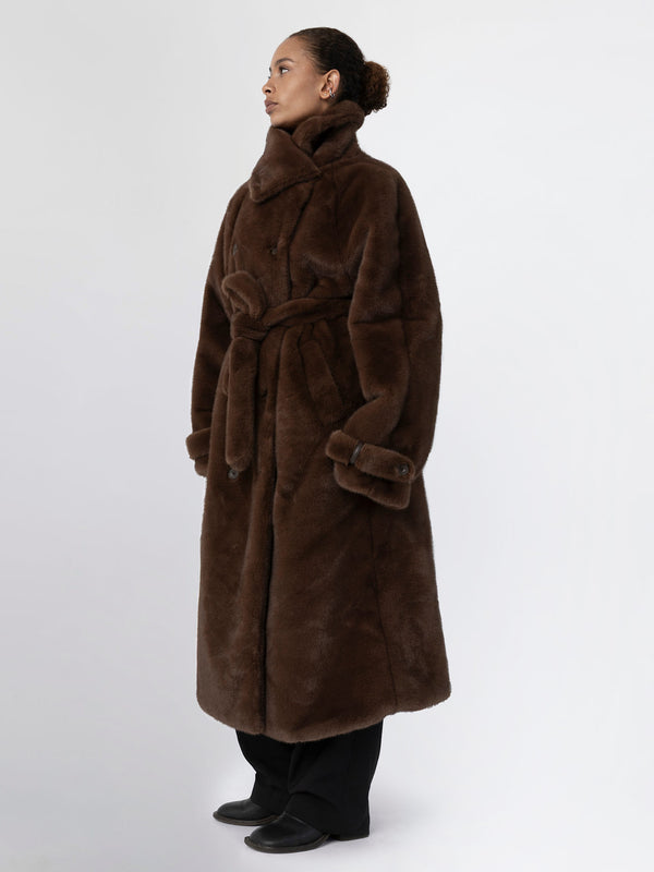 A model showcases a luxurious brown faux fur coat with a belted waist, featuring a high collar and a relaxed fit by MEOTINE.