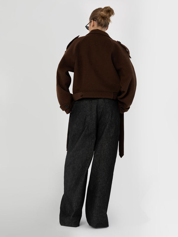 A model wearing a brown oversized jacket and dark wide-leg pants, showcasing a stylish and contemporary look by MEOTINE.