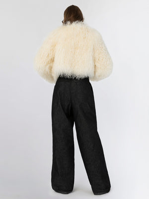 A model wearing a fluffy white MEOTINE jacket paired with high-waisted black trousers, showcasing a stylish back view.