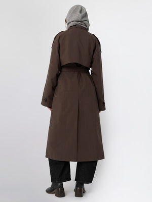 A woman in a brown trench coat with a cropped design, paired with a gray scarf and black wide-leg pants, showcasing MEOTINE style.