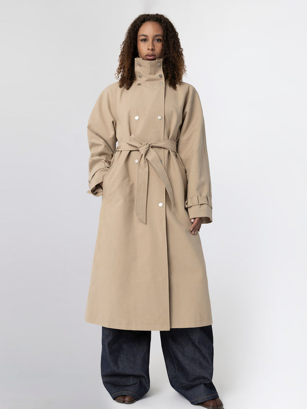 A model wearing a beige trench coat with a belt, paired with wide-leg denim pants, showcasing MEOTINE's stylish outerwear.