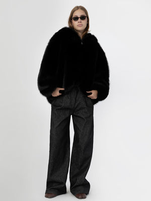 A model wears a stylish black faux fur coat paired with wide-leg dark trousers, showcasing a chic winter look by MEOTINE.