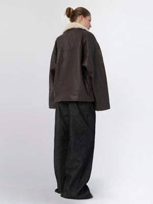 A model showcases a stylish brown leather jacket with a cozy fur collar, paired with loose-fitting dark trousers by MEOTINE.