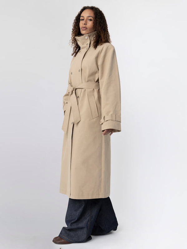 A model showcases a stylish beige trench coat with a belted waist, paired with wide-leg jeans, embodying MEOTINE's chic aesthetic.