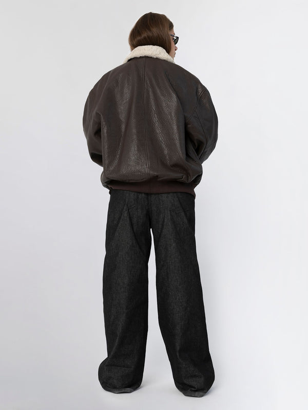 A model wearing a brown oversized leather jacket with a white fur collar and loose black trousers, showcasing MEOTINE's stylish look.