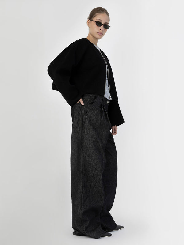 A model showcases a stylish black cropped jacket paired with oversized dark denim pants, embodying MEOTINE's modern aesthetic.