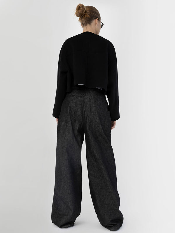 A model wearing a cropped black sweater and wide-leg dark denim pants from MEOTINE, showcasing a stylish back view.