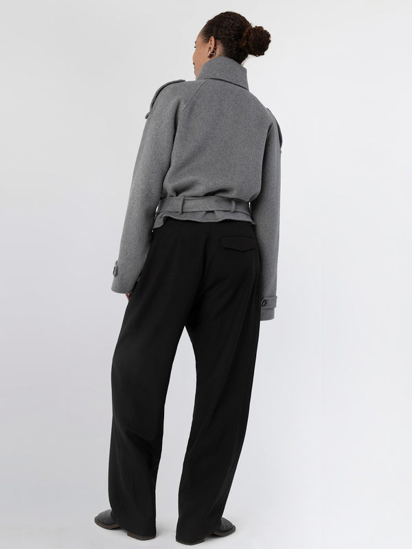A model showcases a stylish gray MEOTINE jacket paired with black wide-leg trousers, highlighting a modern, chic look from the back.