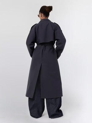 A model wearing a stylish dark trench coat with a cropped design, paired with wide-leg denim pants, showcasing MEOTINE's modern aesthetic.